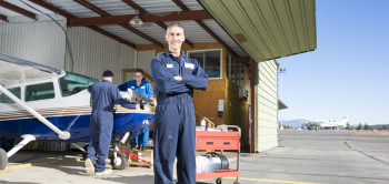 Engineer standing in front of open garage with plane inside